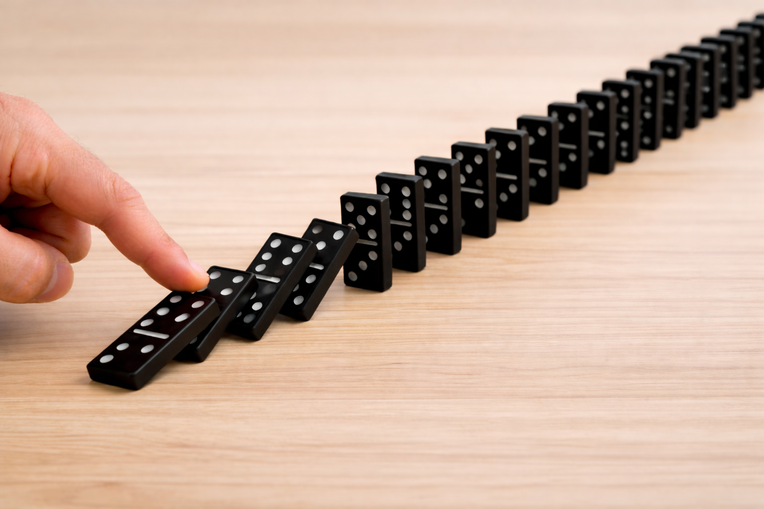 A domino chain reaction illustrates dependent causes unfolding in sequence